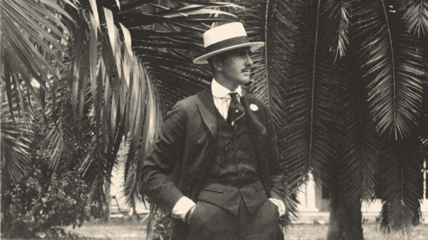 Vintage, black and white photo of a man with a mustache wearing a three-piece suit and hat