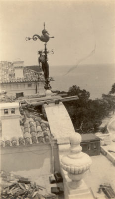 View during construction of the weather vane on top of the Main House. Picture includes a man installing the weather vane.