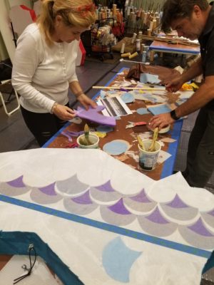 A man and a woman working on a piece from the 2019 Weave Processional Arts Workshop