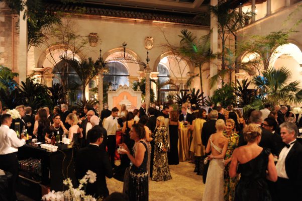 Guests in ball gowns and tuxedos mingle during the cocktail portion of a gala.