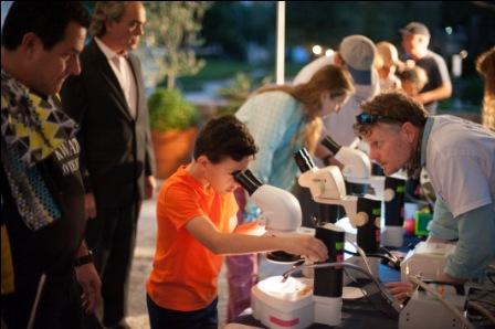 Young boy looks through microscope at Wild Vizcaya: Nocturnal Edition.