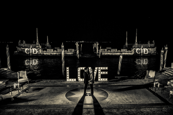A black and white photo of a couple standing in front of a sign that says love.