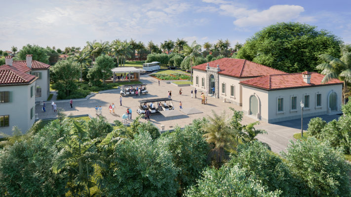 Arial view of Vizcaya's historic Garage forecourt. Three coral-colored buidings with barrel tile roofs. In the center court, people are walking around, while some people have boarded two covered trams.