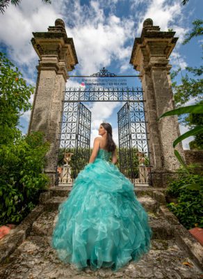 Beautiful brunette in a tiara and turqouise dress poses for quince photos in Vizcaya's gardens. Photos by Ernesto S. Cachan of Cachan Inc.