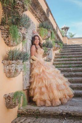 Beautiful quinceañera posing in a ruffled cream-colored dress in the Secret Garden. Photo by Life Stories Photography