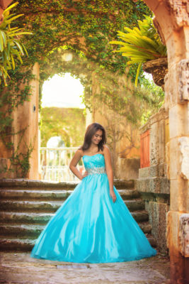 Young lady in blue, strapless ball gown poses for her quince photos in the Secret Garden at Vizcaya. Photo by Michael Reyes of K Ro Photography