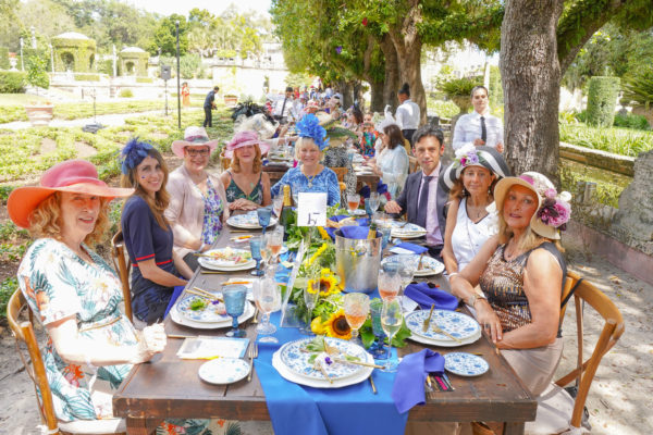 Ladies wearing spring dresses and hats sit for lunch in the gardens.