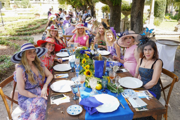 Ladies wearing spring dresses and hats sit for lunch in the gardens.