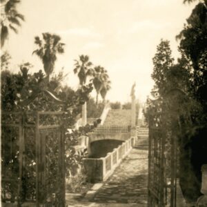 A black and white photo of a gate to a park.