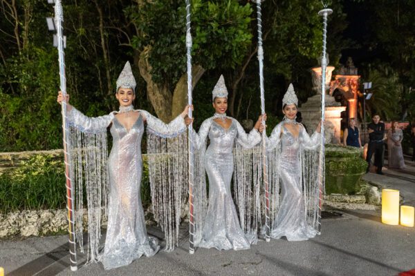 Four women in silver costumes standing on a red carpet at the Vizcaya Ball.