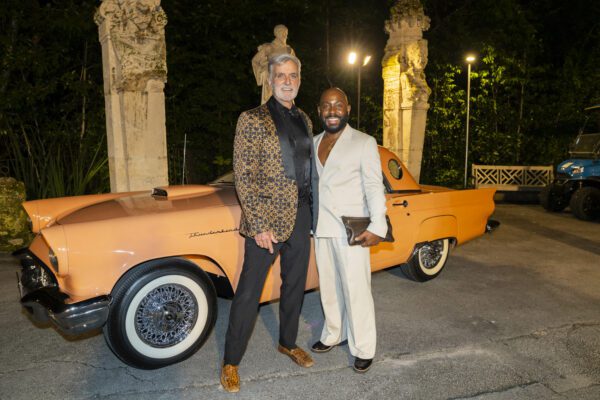Two men standing next to an orange classic car at the Vizcaya Ball.