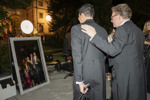 Two men in tuxedos standing in front of a mirror at the Vizcaya Ball.
