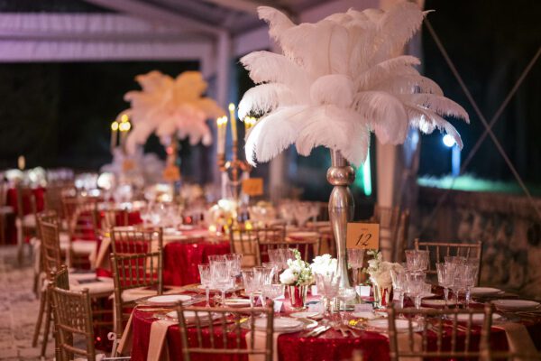 A vibrant Vizcaya Ball with red and white tablecloths exuding elegance and adorned with feathers.