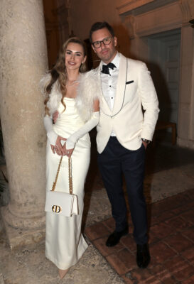 A man and a woman in a white tuxedo and dress respectively attending the Vizcaya Ball.