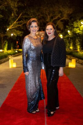 Two women standing on a red carpet at the Vizcaya Ball.
