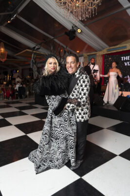 A man and woman gracefully standing on a black and white checkered floor at the Vizcaya Ball.