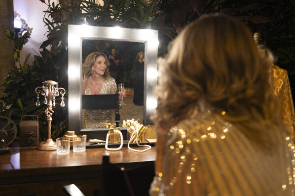A woman preparing for the Vizcaya Ball, admiring her reflection in a mirror.