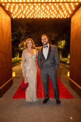 A man and woman elegantly standing on a red carpet at the Vizcaya Ball.