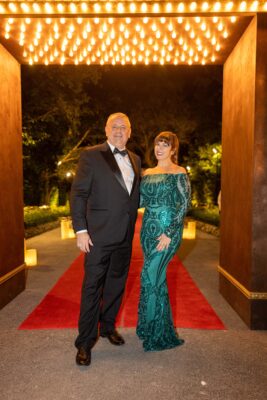 A man and woman standing in front of a red carpet at the Vizcaya Ball.