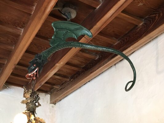 A dragon hanging from the ceiling of a room being used as a light fixture.
