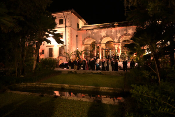 A group of people attending the Vizcaya Ball, standing in front of a house at night.