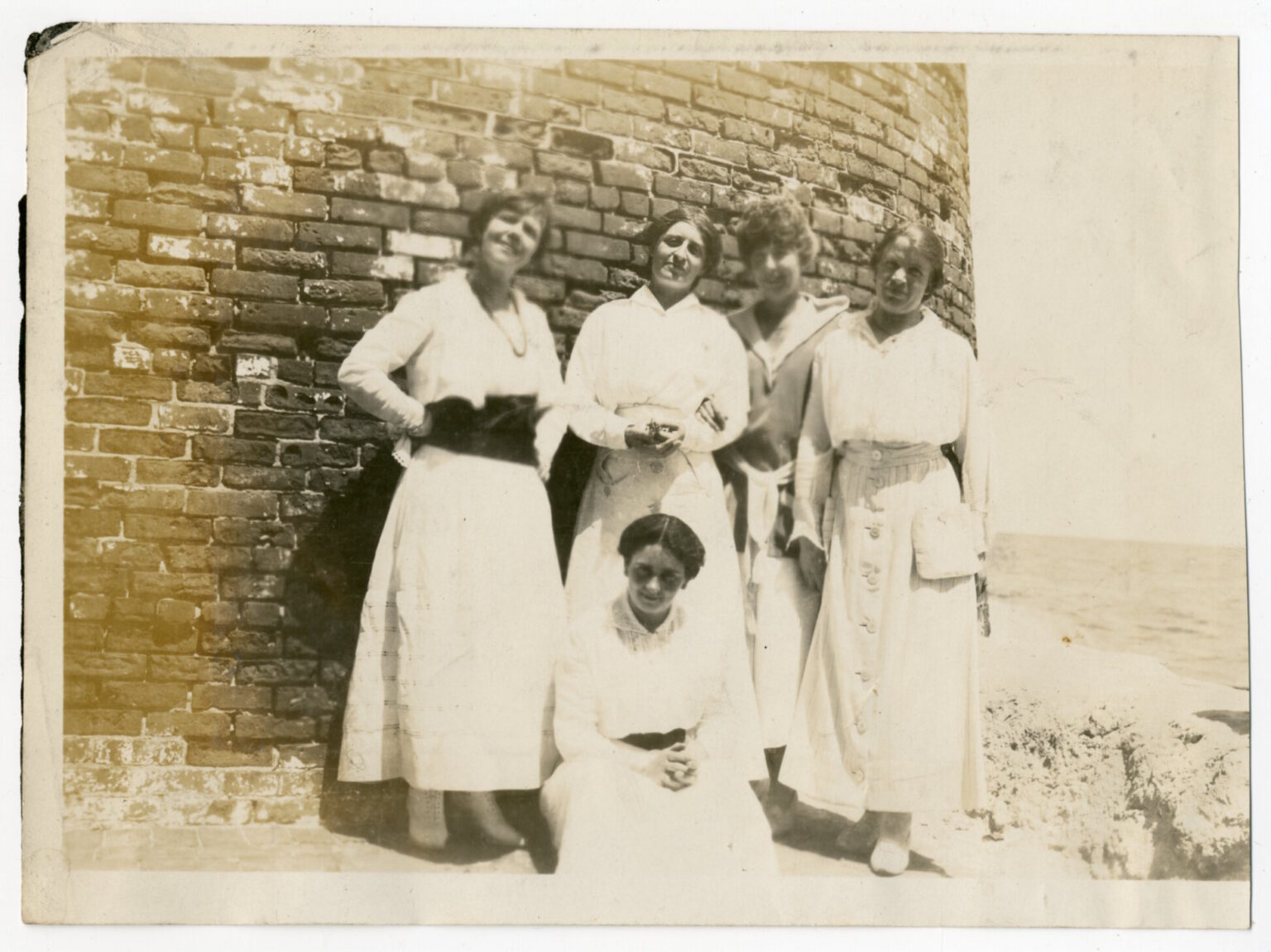 Four women posing in front of a brick wall.