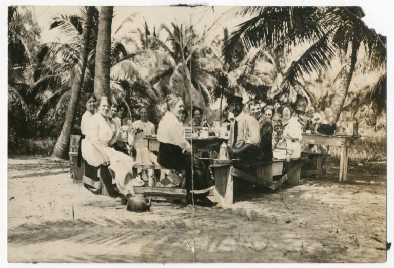 A group of people sitting around a table on the beach.